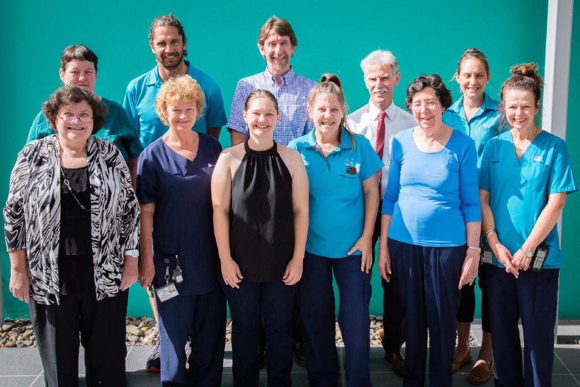 The Coffs Harbour team standing in front of a teal wall